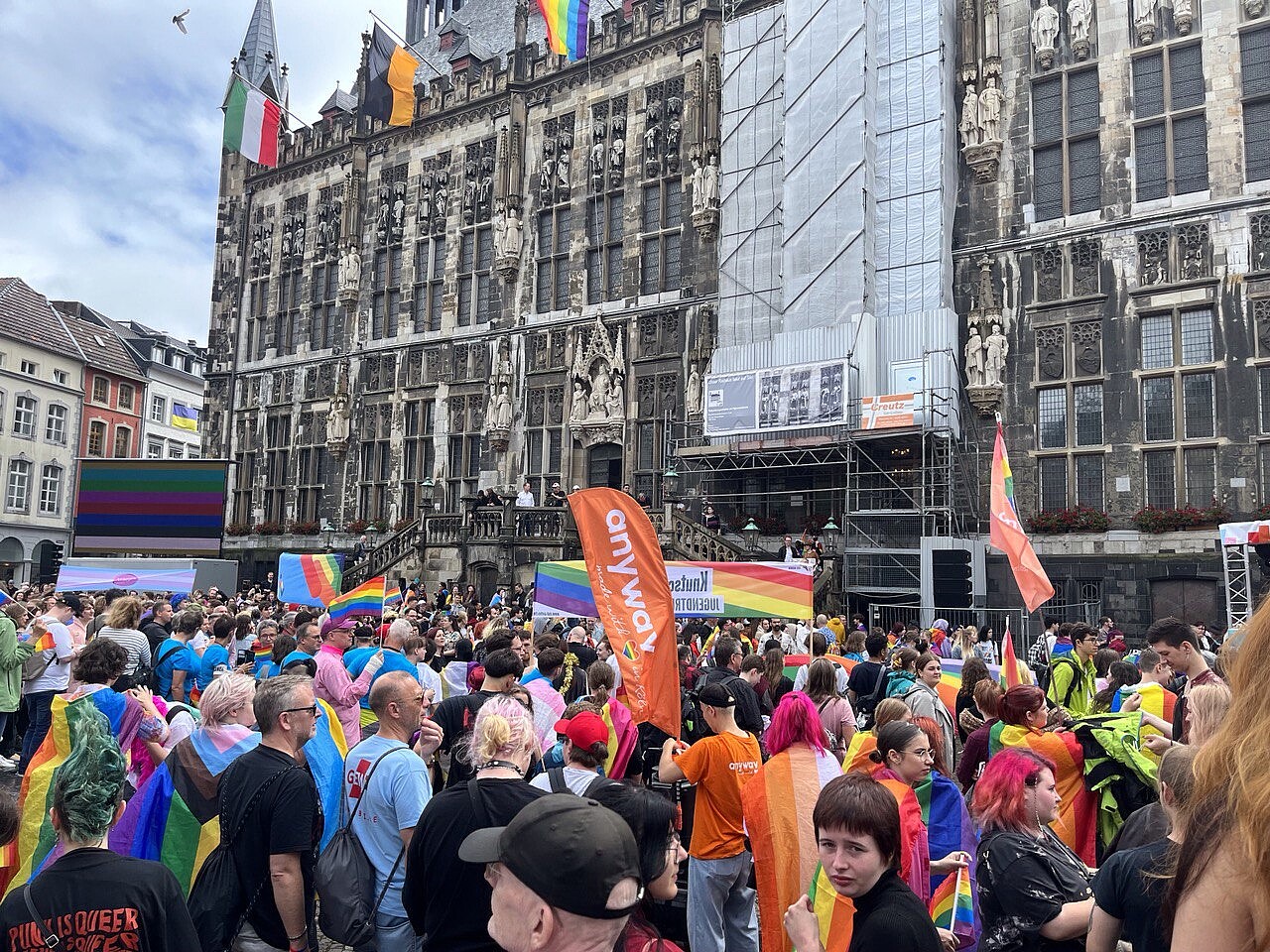 Menschen mit Regenbogenfahnen auf dem Markt vor dem Aachener Rathaus