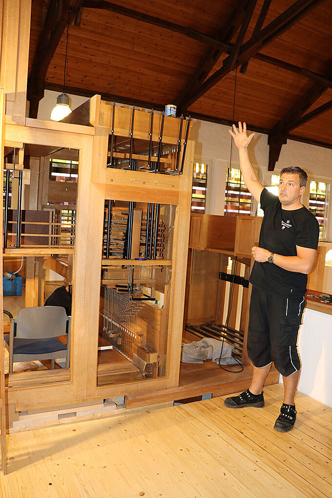 Orgelbauer Reich erläutert die Teile der Schumacher-Orgel, die er gerade in der Martin-Luther-Kirche aufbaut.