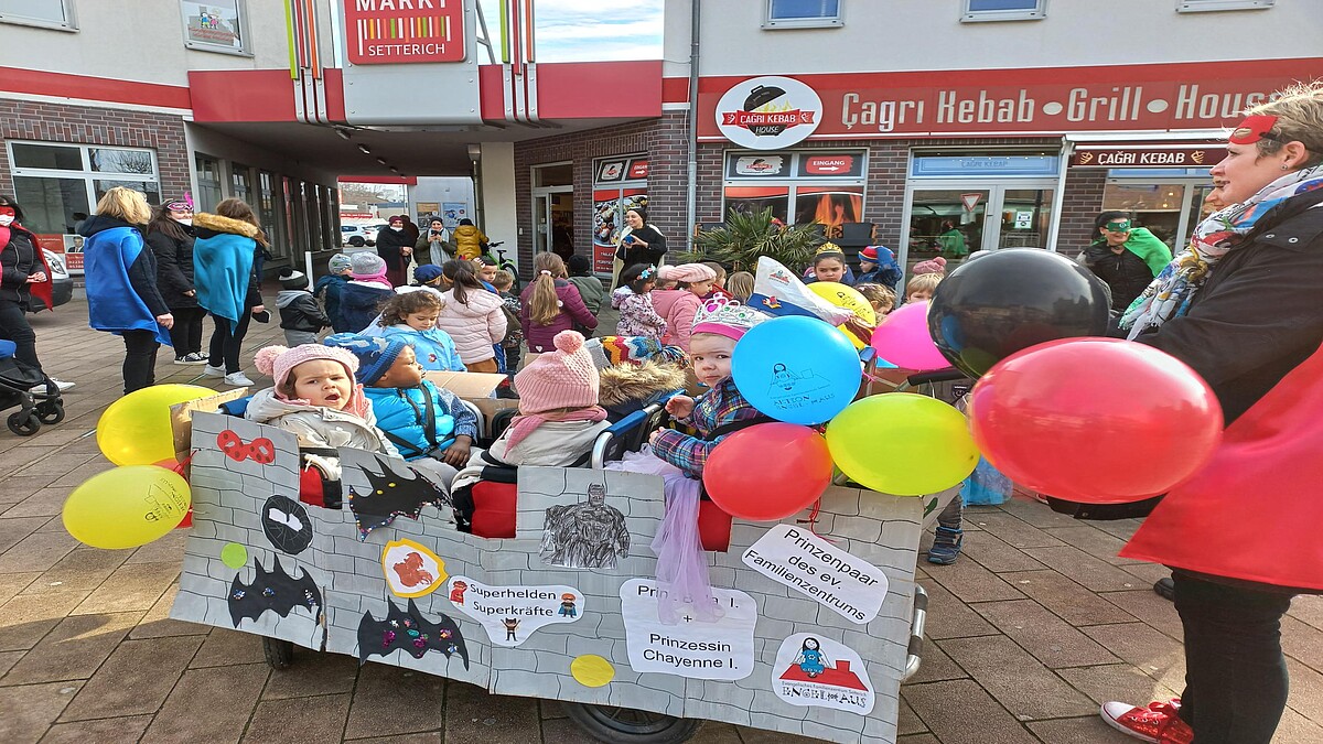 Ein bunt geschmückter Karnevalswagen im Miniaturformat mit einem fröhlichen dreijährigen Prinzenpaar.